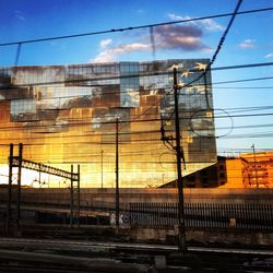 Electricity pylon in city against sky during sunset