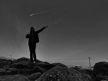 Rear view of man standing on rock against sky