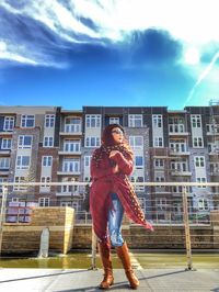 Full length of woman smiling against sky in city