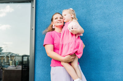 Portrait of smiling girl standing against wall