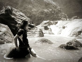 Woman standing by rock at river