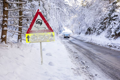 Road sign warns of ice and snow at winter