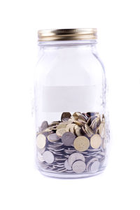 Close-up of coins in jar against white background