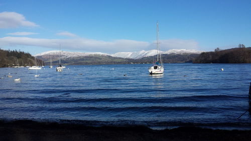 Boats sailing in sea against blue sky