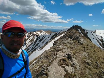 Portrait of smiling man standing by mountain against sky