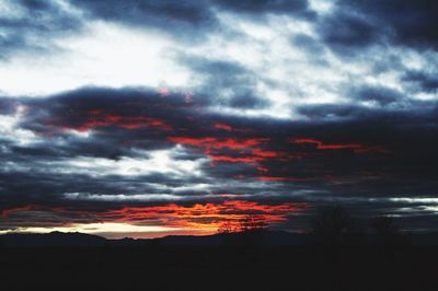 Low angle view of storm clouds over silhouette landscape