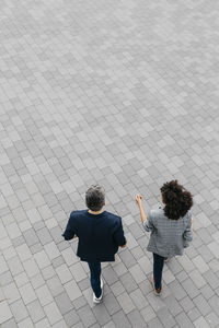 Top view of two colleagues walking on a square
