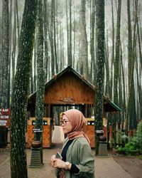 Rear view of man holding ice cream cone against trees in forest