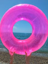 Close-up of pink umbrella on beach against sky