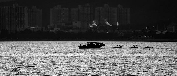 People on sea by buildings in city at night