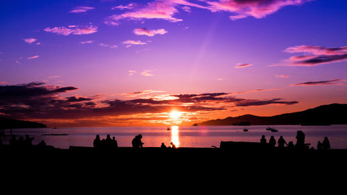 Silhouette people on beach against sky during sunset