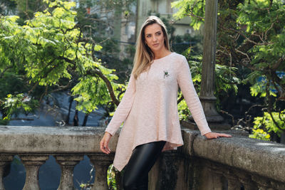 Woman looking away while standing by retaining wall