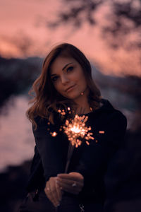 Portrait of beautiful young woman standing against sky during sunset