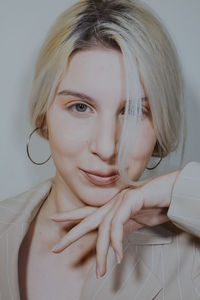 Close-up of young woman wearing blazer against wall