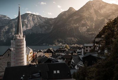 Townscape and mountains by lake against sky