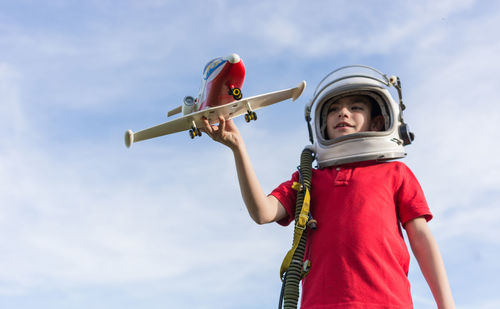 Low angle view of child holding umbrella against sky