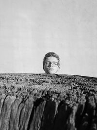 Surreal black and white photo of teenage boys head on a tree stump