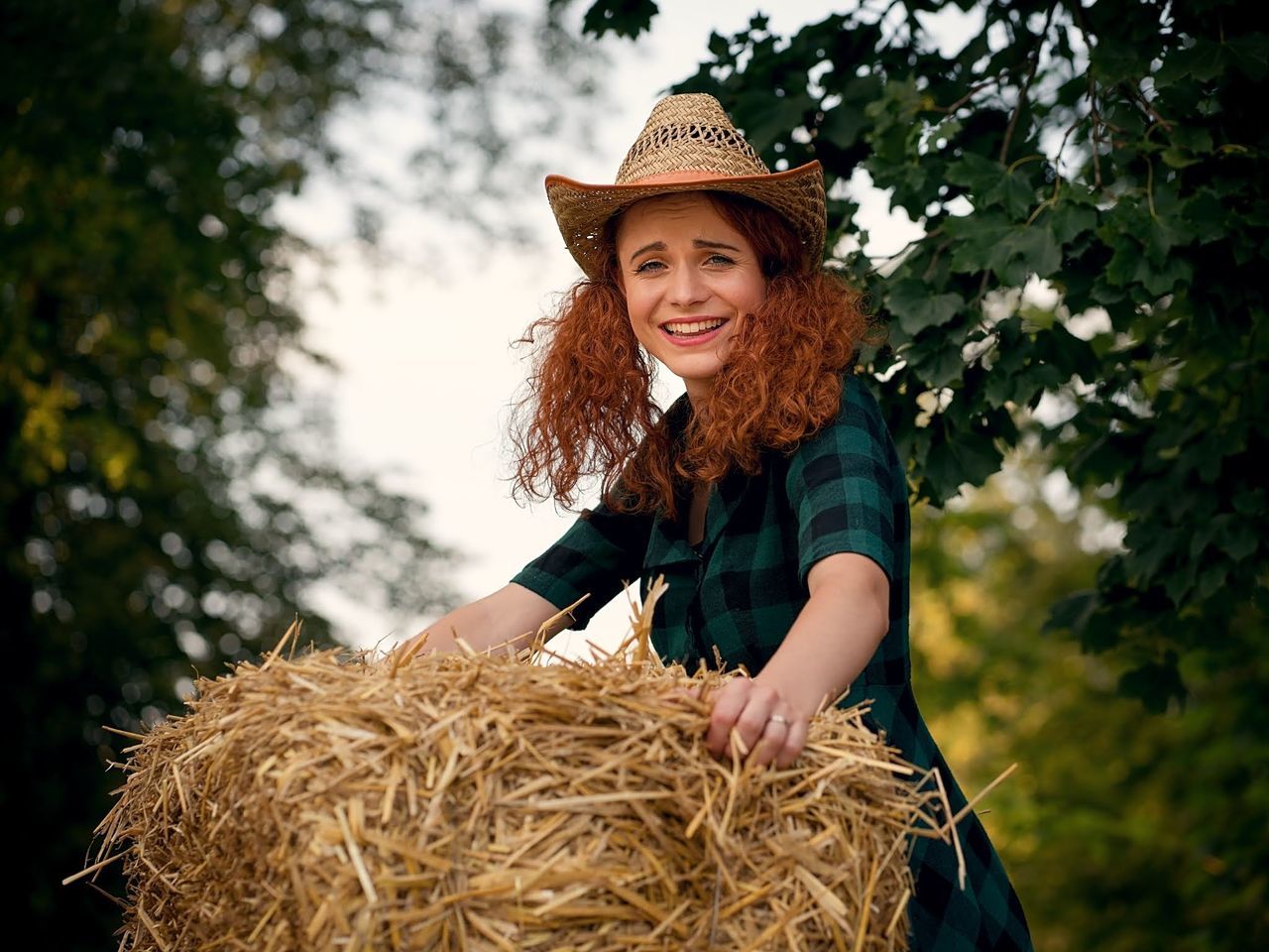 agriculture, smiling, plant, one person, adult, happiness, farm, hat, rural scene, women, nature, portrait, clothing, emotion, straw, landscape, harvesting, tree, cheerful, farmer, hay, looking at camera, autumn, long hair, straw hat, bale, hairstyle, person, crop, young adult, sun hat, day, lifestyles, smile, casual clothing, female, teeth, outdoors, growth, summer, occupation, flower, land, cowboy hat, fashion accessory, field, redhead, leisure activity, fashion, grass, waist up, food, positive emotion, food and drink, organic