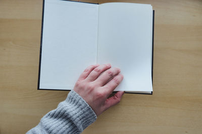 Midsection of person holding book on table