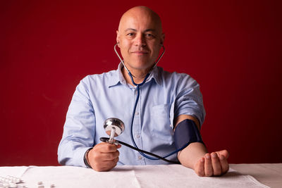 Portrait of man sitting on table against red background