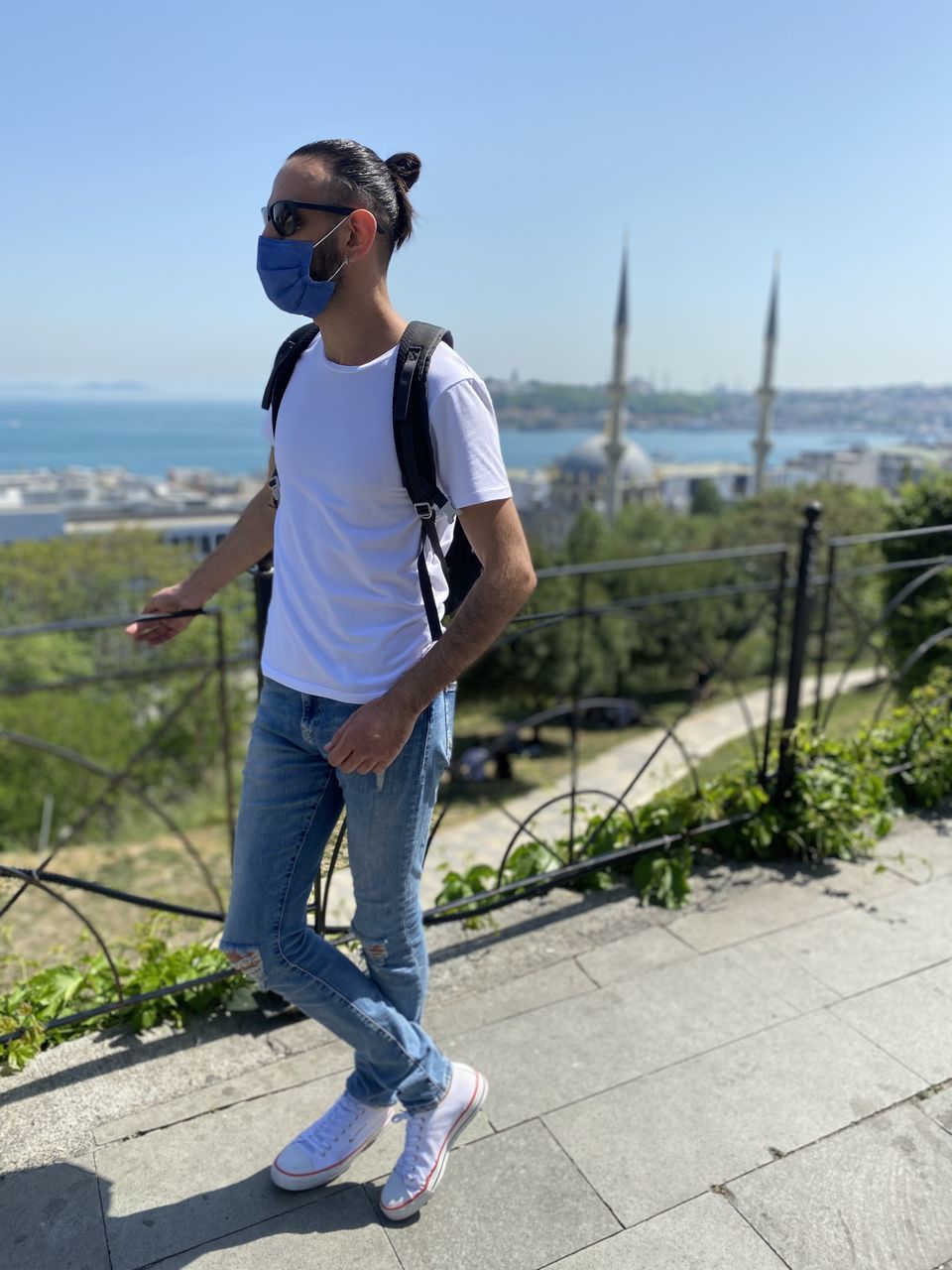 YOUNG MAN WEARING SUNGLASSES STANDING ON RAILING AGAINST SKY