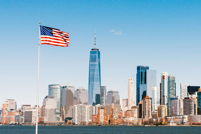 Flags on modern buildings in city against sky