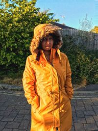 Portrait of woman standing against trees in city