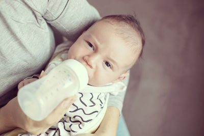 Cropped image of mother feeding milk to baby boy