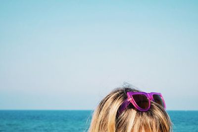 Cropped image of woman with purple sunglasses on head against sky