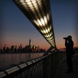 Man photographing cityscape against clear sky during sunset