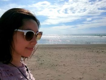 Close-up of young woman at beach against sky