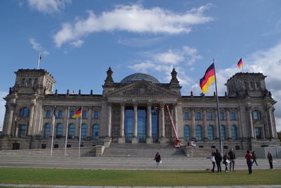 Group of people in front of historical building against sky