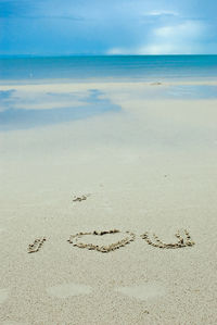 Close-up of heart shape on beach against sky