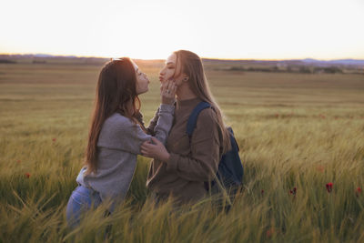 Two women holding hands at sunset in the field