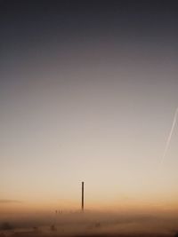 Factory on foggy field against sky during sunset