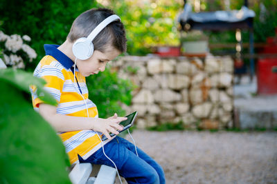 Cute boy listening music while using mobile phone at cafe