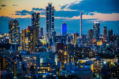 Illuminated buildings in city against sky at night