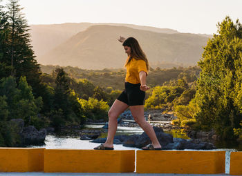 Woman standing on mountain against trees