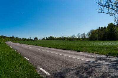 Empty road along trees on field