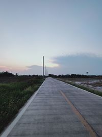 Empty road amidst land against sky during sunset