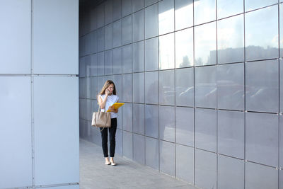 Woman standing against wall of building