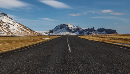 Empty road by mountain against sky