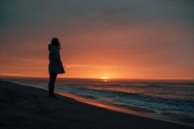 Woman standing on beach during sunset