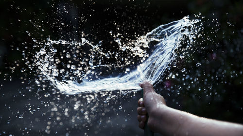 Cropped image of hand spraying water outdoors