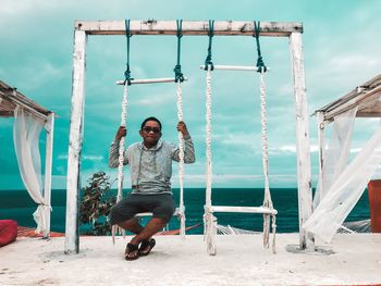 Portrait of young man sitting on swing