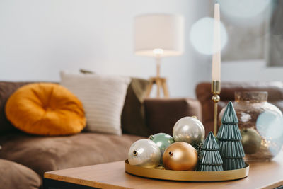 Christmas decor on the table of livingroom. baubles and christmas small toy trees on tray by sofa 