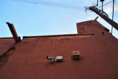 Low angle view of telephone pole and camera against sky