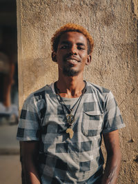 Portrait of young man standing against wall