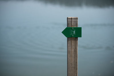 Close-up of sign on wooden post in lake