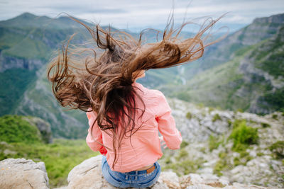 Young woman looking at mountain against sky